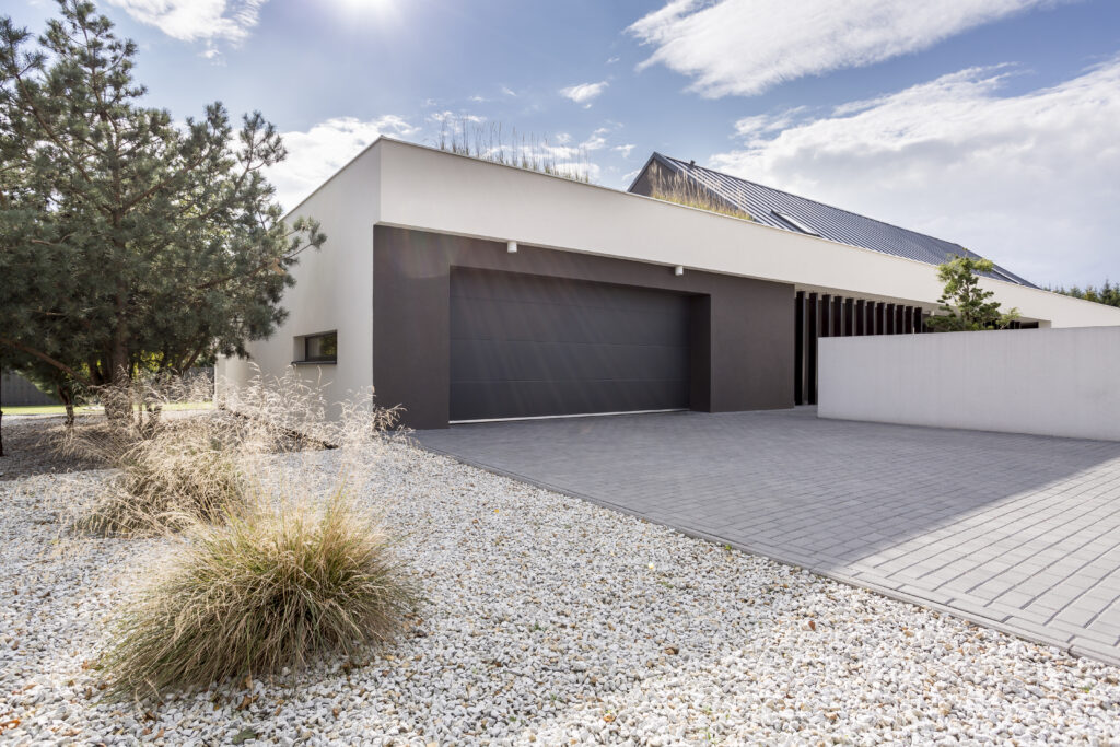 Contemporary home exterior featuring a flat roof, modern garage door, minimalist landscaping, and clean architectural lines.