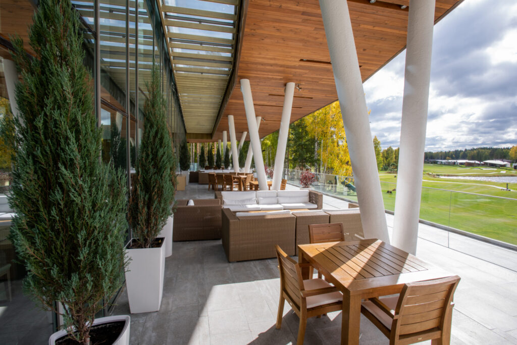 Modern golf clubhouse patio with outdoor seating, wood finishes, and expansive course views before renovation or upgrades.