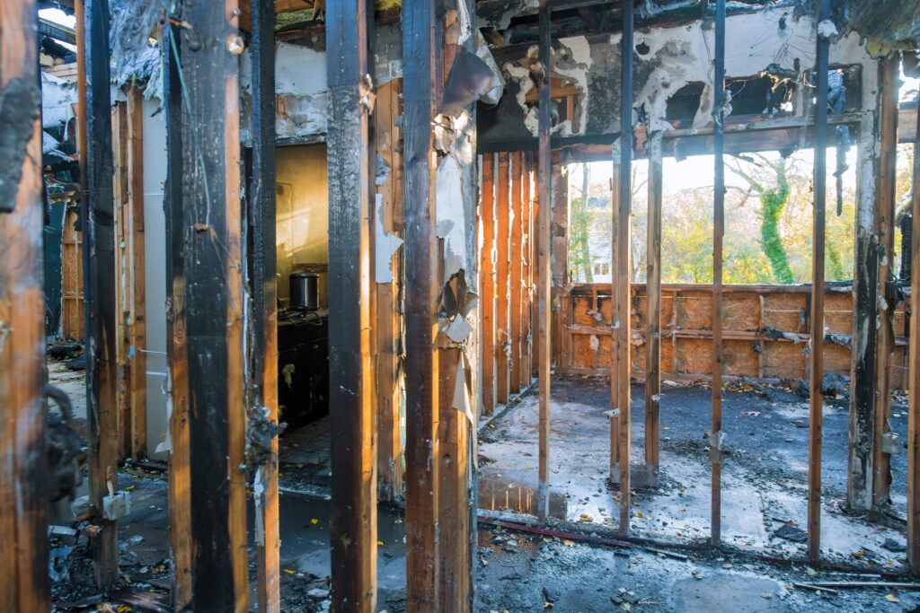 Interior of a home severely damaged by fire, showing burned studs, exposed framing, and structural loss before fire restoration and reconstruction work.